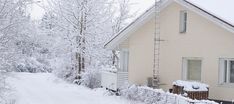 a house covered in snow next to a tree