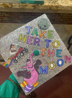 a decorated graduation cap with the words take her to the moon on it and an image of a cartoon character