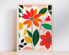 an art print with colorful flowers and leaves on a white wall above a wooden shelf