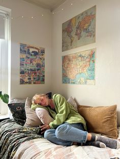 a woman laying on top of a bed next to a map hanging above her head