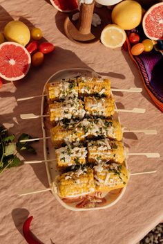 an assortment of food on skewers sitting on a table next to oranges and other fruits