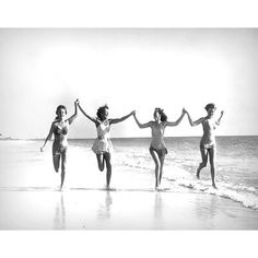 four women running on the beach with their arms in the air