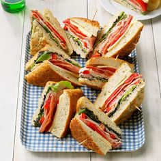 several sandwiches are arranged on a blue and white checkered plate with toothpicks