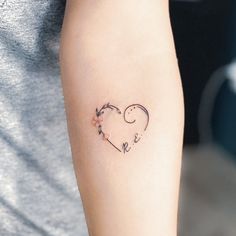 a woman's arm with a small heart tattoo on it