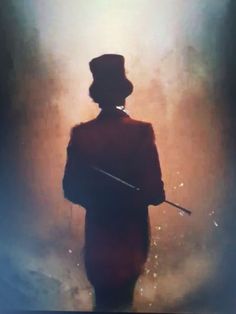 the silhouette of a man with a top hat and cane in front of a foggy background