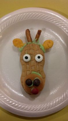 a white plate topped with a cookie shaped like a reindeer's head and eyes