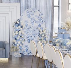 a dining room with blue and white flowers on the wall, gold chairs and tables