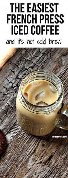 a glass jar filled with liquid sitting on top of a wooden table next to cookies