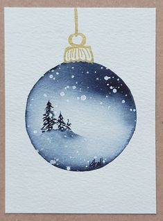 a watercolor christmas ornament with a snowy scene on the front and bottom