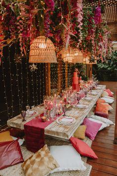 a long table is set up with pink and orange pillows, candles, and other decorations