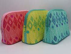 three different colored cosmetic bags sitting next to each other