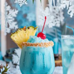 a blue drink with a pineapple on the rim and a cherry in the middle