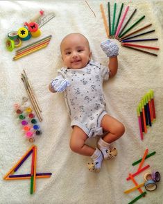 a baby laying on top of a blanket next to crayons and pencils