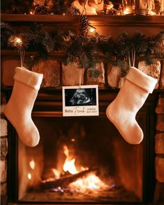 two stockings hanging from a fireplace next to a fire place with an old photo on it