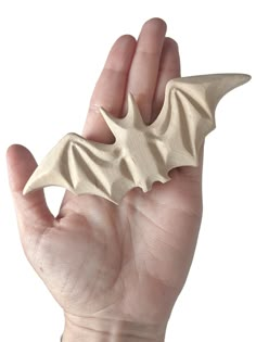 a hand is holding a carved object in it's right hand and the other hand has a small bat on it