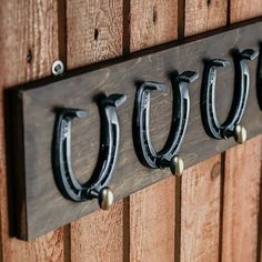 three black metal hooks are hanging on a wooden wall