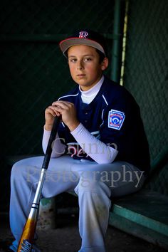 a young boy sitting on a bench holding a baseball bat