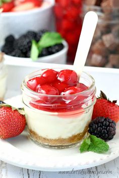 there is a dessert with berries in the jar on the plate and strawberries next to it