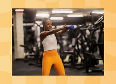 a woman holding a blue object in her right hand while standing next to a gym machine