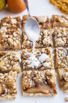 a spoon is being drizzled with icing over some dessert squares and pears