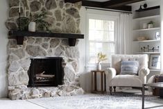 a living room filled with furniture and a fire place in front of a stone wall