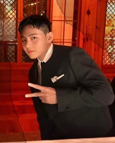 a boy in a suit pointing at something