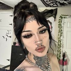 a woman with black hair and piercings on her face is posing for the camera