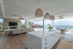 a large open concept living room and dining area with ocean view in the back ground