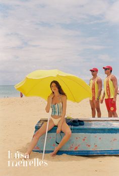 two men and a woman on the beach with an umbrella in front of their heads