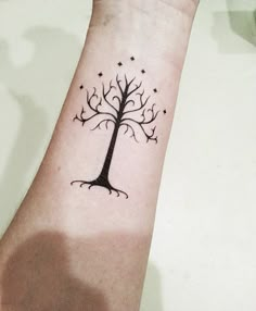 a small tree tattoo on the wrist with stars around it and an arrow in the middle