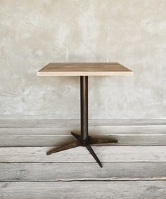 a small table sitting on top of a wooden floor next to a white brick wall