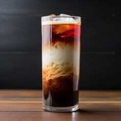 a tall glass filled with liquid on top of a wooden table