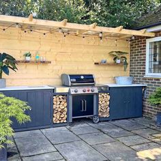 an outdoor bbq with wood stacked on the grill and shelves above it, along with potted plants