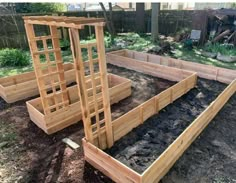 several wooden raised garden beds in the middle of a yard with dirt on the ground