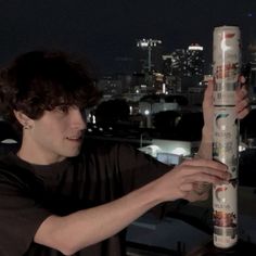 a person holding up a tall tube in front of a cityscape at night