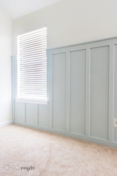 an empty room with white walls and blue shutters on the windowsill, carpeted floor