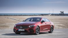 a red mercedes cla is parked on the beach