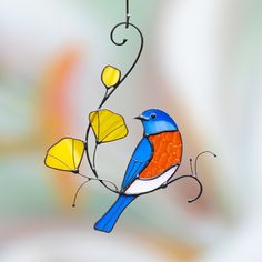 a stained glass bird sitting on a branch with yellow flowers