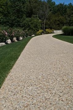 there is a gravel path in the middle of some grass and flowers on either side