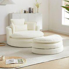 a living room with white furniture and large plants in the corner on the rugs