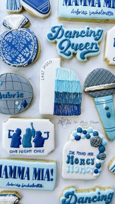 cookies decorated with blue and white icing are displayed on a counter top, including one that says dancing queen