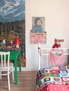 a child's room with a bed, desk and chair in it that has a painting on the wall