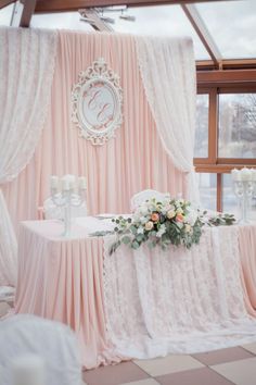 the table is set up for a wedding reception with pink drapes and white flowers