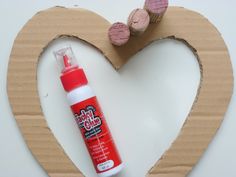 a heart shaped cardboard frame with glue on it and two small wooden hearts in the background