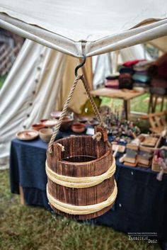 a wooden bucket hanging from a rope in front of a tent