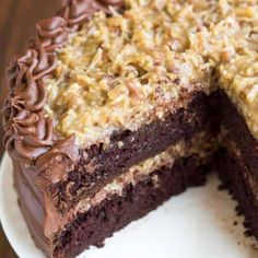 a chocolate cake with walnuts and crumbs cut in half on a white plate