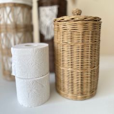 two rolls of toilet paper sitting on top of a table next to a wicker basket