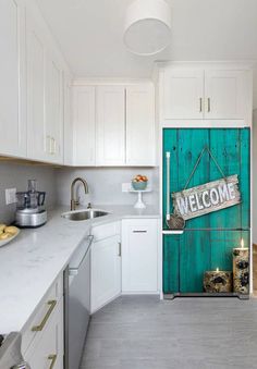 a welcome sign is hanging on a door in a kitchen with white cabinets and countertops