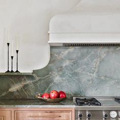 two apples in a bowl sitting on top of a kitchen counter next to an oven