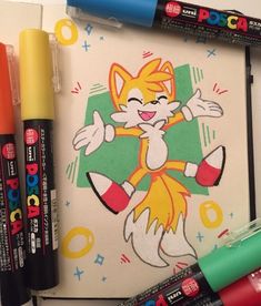 some markers and pens are laying on top of a drawing book with an image of a cartoon cat